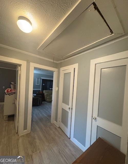 corridor with hardwood / wood-style flooring, a textured ceiling, and ornamental molding