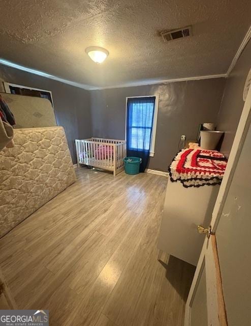 bedroom with hardwood / wood-style flooring, a textured ceiling, and ornamental molding