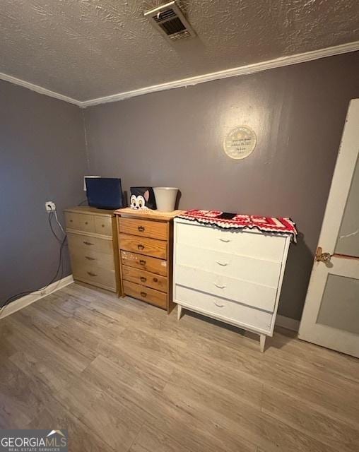 unfurnished bedroom featuring ornamental molding, light hardwood / wood-style flooring, and a textured ceiling