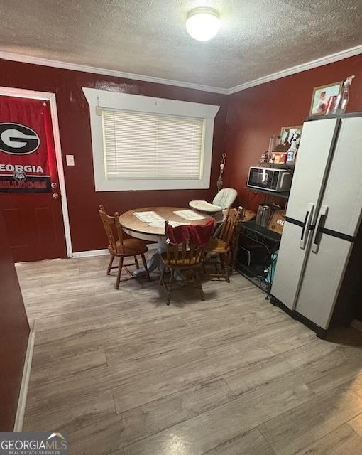 dining space with crown molding, light hardwood / wood-style flooring, and a textured ceiling