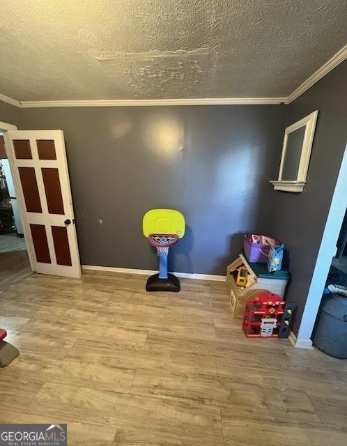 recreation room with wood-type flooring, crown molding, and a textured ceiling