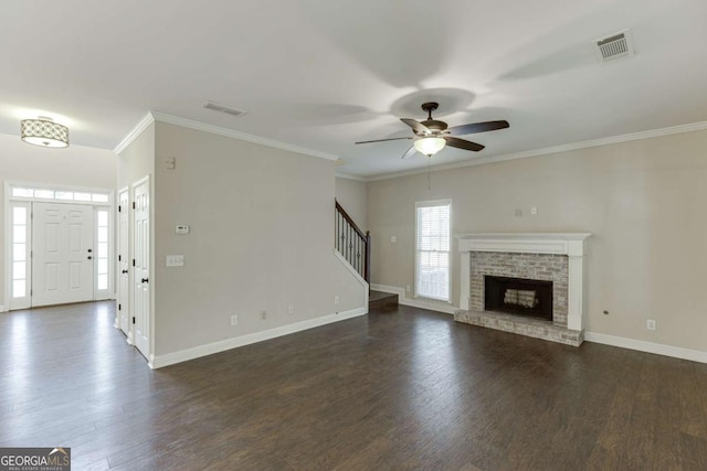 unfurnished living room with a brick fireplace, dark hardwood / wood-style floors, crown molding, and ceiling fan