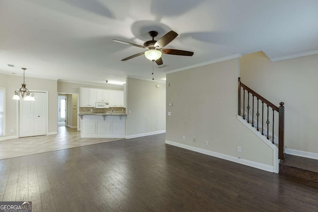 unfurnished living room featuring ceiling fan with notable chandelier, ornamental molding, and dark hardwood / wood-style floors