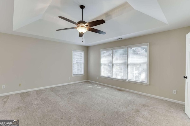 carpeted spare room with ceiling fan and a tray ceiling