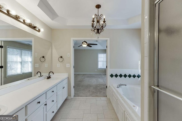 bathroom with a tub, a healthy amount of sunlight, tile patterned floors, and a raised ceiling