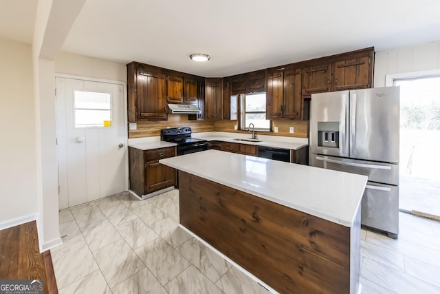 kitchen featuring black appliances, a kitchen island, dark brown cabinetry, and sink