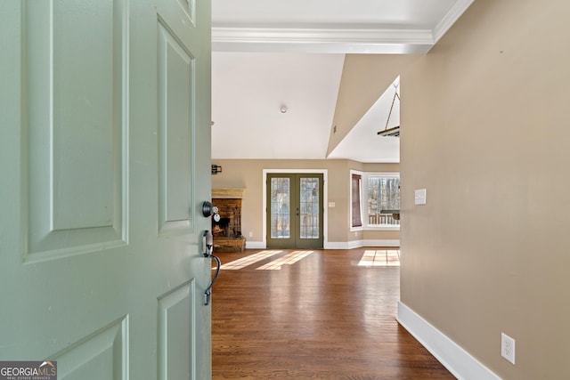 foyer entrance with crown molding, a fireplace, french doors, and dark wood-type flooring