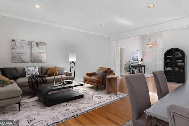 living room with light hardwood / wood-style flooring, ornamental molding, and ornate columns