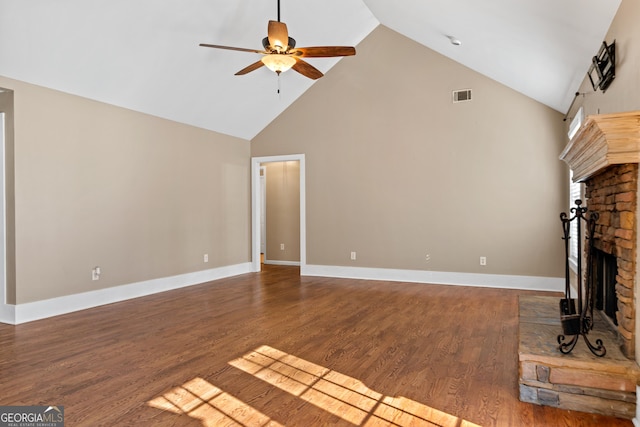 unfurnished living room featuring a stone fireplace, dark hardwood / wood-style floors, high vaulted ceiling, and ceiling fan