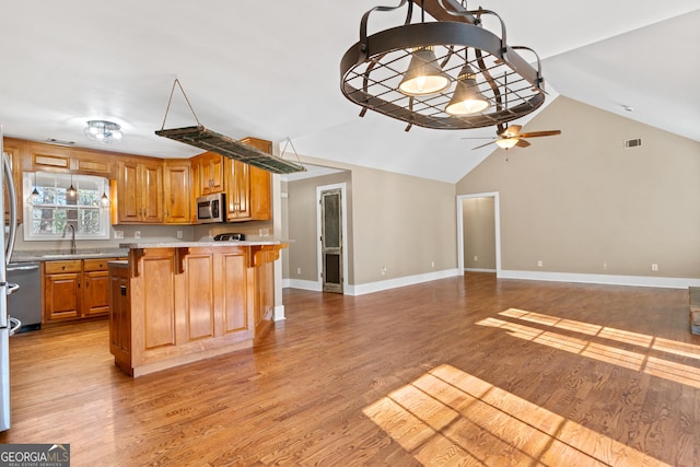 kitchen featuring sink, a center island, light hardwood / wood-style flooring, appliances with stainless steel finishes, and a kitchen breakfast bar