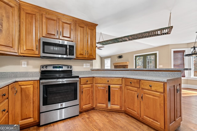 kitchen featuring lofted ceiling, light hardwood / wood-style flooring, hanging light fixtures, stainless steel appliances, and kitchen peninsula