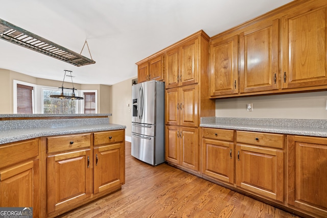 kitchen featuring hanging light fixtures, stainless steel fridge, and light wood-type flooring