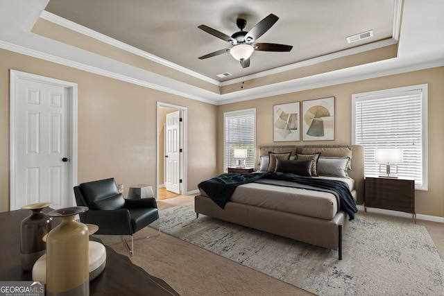 carpeted bedroom featuring crown molding, ceiling fan, and a raised ceiling