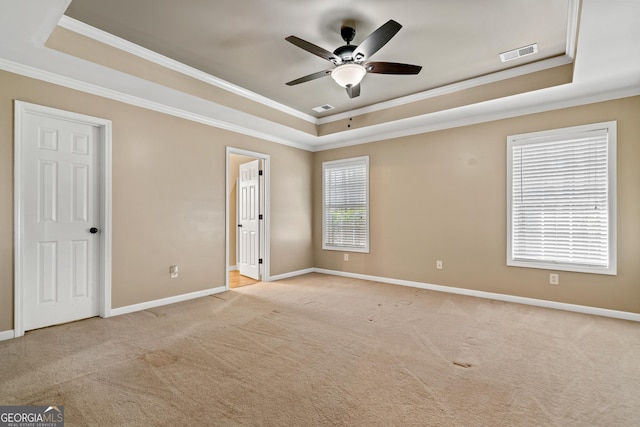 carpeted spare room featuring a raised ceiling, ornamental molding, and ceiling fan