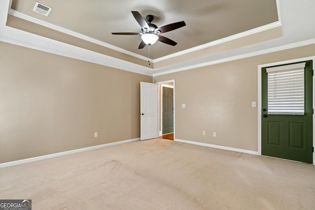 spare room featuring ceiling fan, light colored carpet, ornamental molding, and a raised ceiling