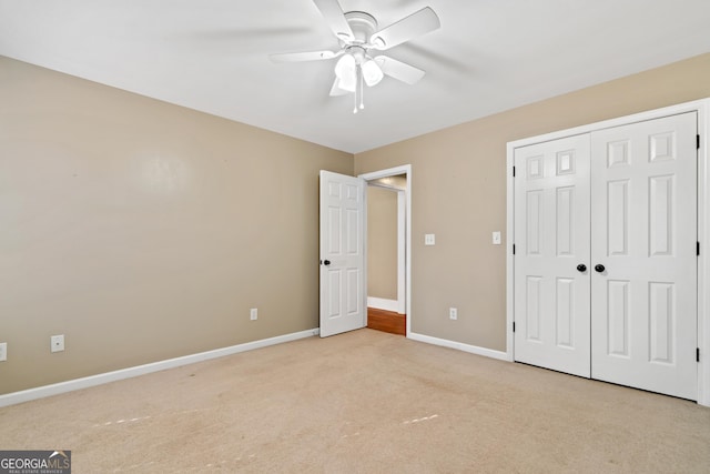 unfurnished bedroom featuring ceiling fan, light colored carpet, and a closet