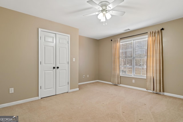 unfurnished bedroom featuring light carpet, a closet, and ceiling fan