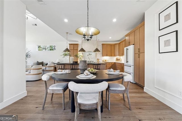 dining room featuring light wood-type flooring and a notable chandelier