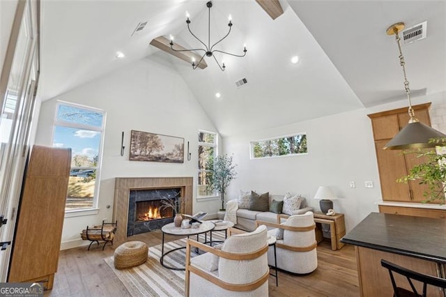 living room with high vaulted ceiling, an inviting chandelier, and light wood-type flooring