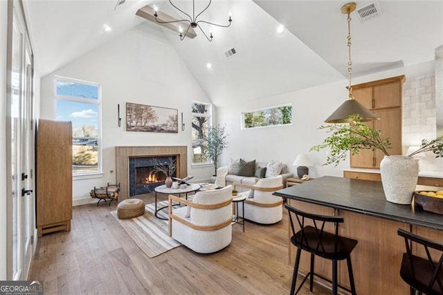 living room featuring high vaulted ceiling, light hardwood / wood-style floors, and a notable chandelier