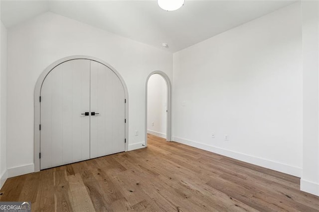 unfurnished bedroom featuring light hardwood / wood-style floors and lofted ceiling