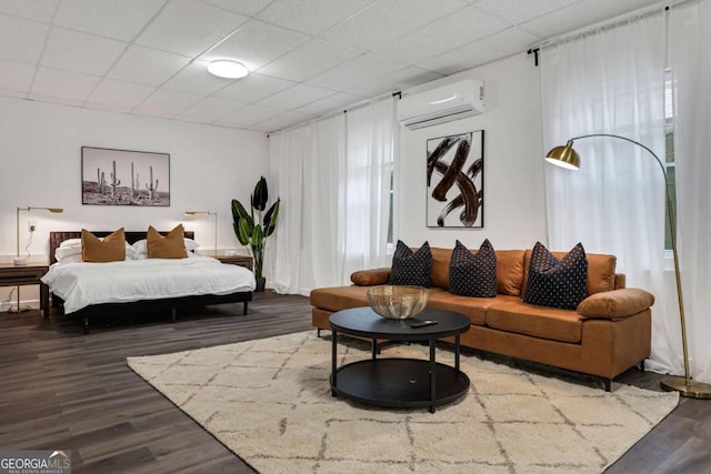 bedroom with dark wood-type flooring, a drop ceiling, and a wall unit AC