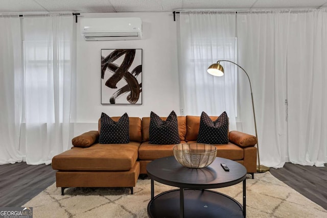 living room featuring a drop ceiling, hardwood / wood-style flooring, and a wall unit AC