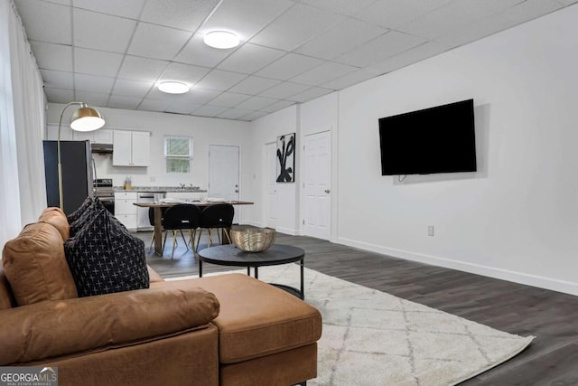 living room with a paneled ceiling and dark wood-type flooring