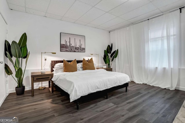 bedroom featuring a paneled ceiling and dark hardwood / wood-style floors