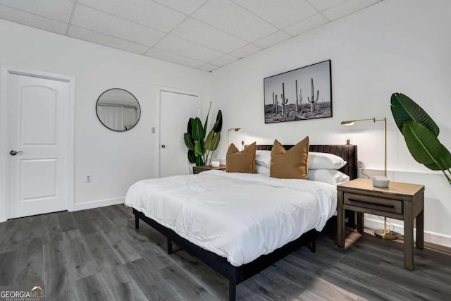 bedroom featuring a drop ceiling and dark hardwood / wood-style floors