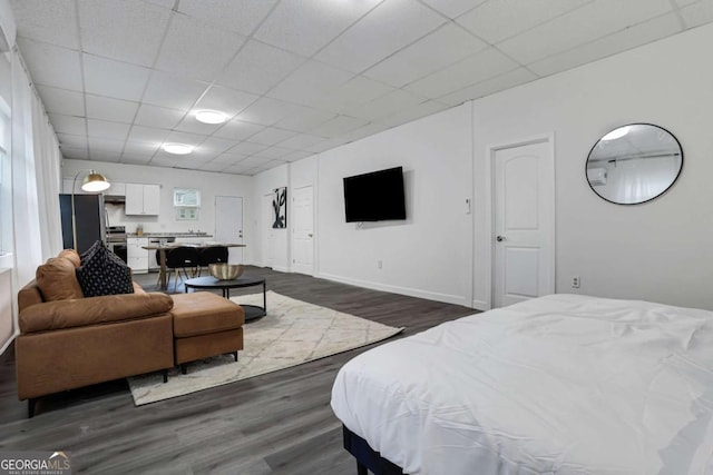 bedroom featuring a drop ceiling, dark hardwood / wood-style floors, and stainless steel refrigerator