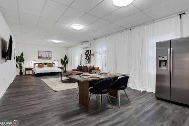 dining space with an AC wall unit, a drop ceiling, and dark hardwood / wood-style floors