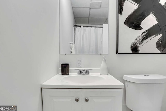 bathroom with a paneled ceiling, toilet, a shower with shower curtain, and vanity