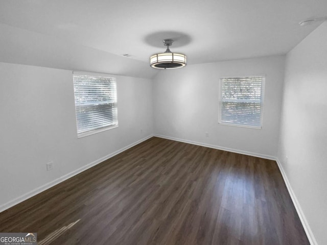 empty room featuring dark wood-type flooring and plenty of natural light