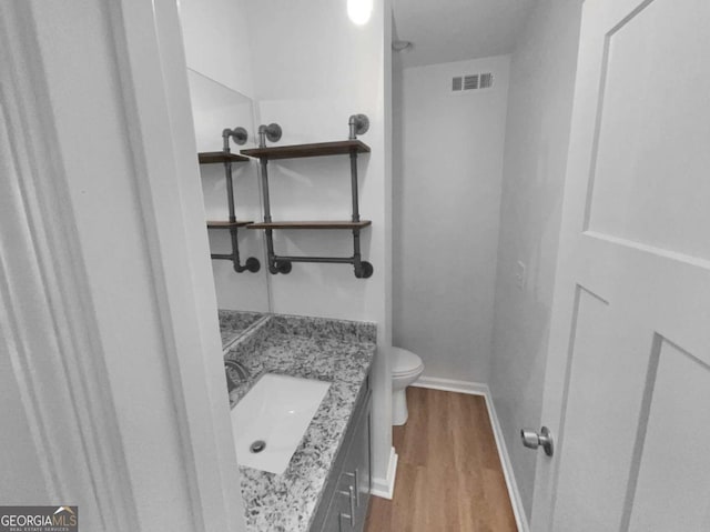 bathroom with wood-type flooring, toilet, and vanity