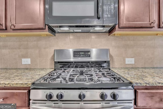 kitchen featuring decorative backsplash, light stone countertops, and gas stove
