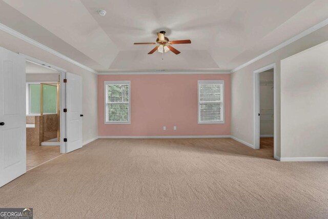 unfurnished bedroom featuring ceiling fan, a raised ceiling, a spacious closet, and light carpet