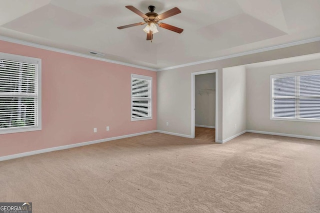 empty room featuring crown molding, light colored carpet, and a tray ceiling