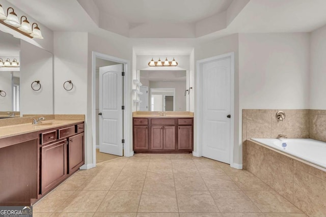 bathroom featuring vanity, a tray ceiling, tiled bath, and tile patterned flooring