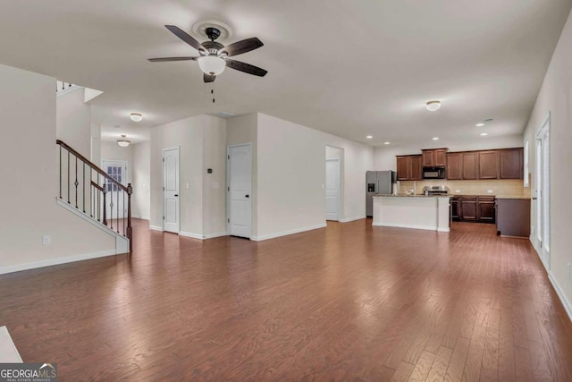 unfurnished living room with ceiling fan and dark wood-type flooring