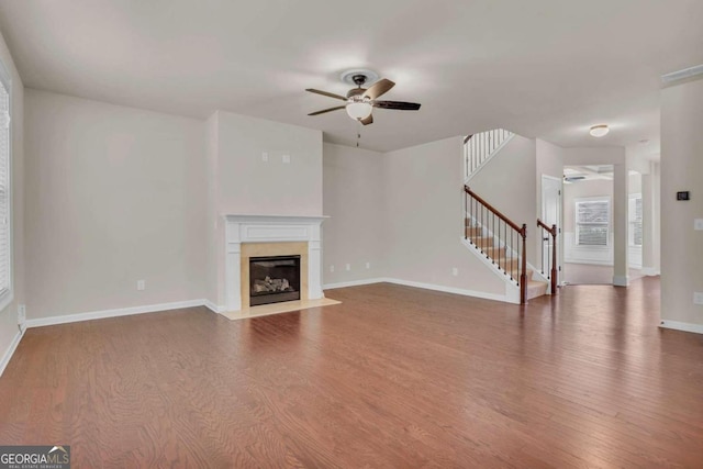 unfurnished living room with a premium fireplace, hardwood / wood-style flooring, and ceiling fan