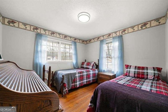 bedroom featuring a textured ceiling, multiple windows, and wood-type flooring