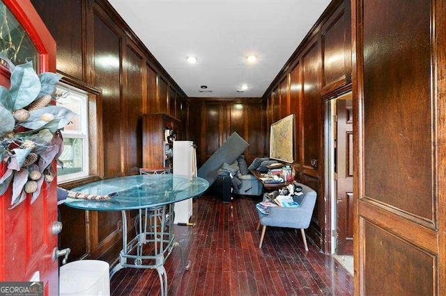 kitchen featuring wood walls, crown molding, dark hardwood / wood-style floors, and a breakfast bar