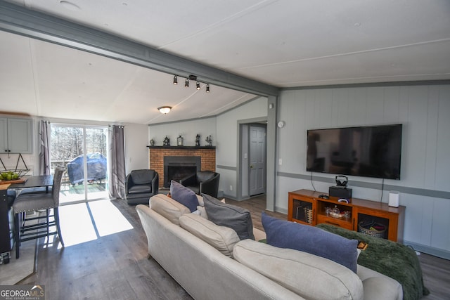 living room with vaulted ceiling with beams, dark hardwood / wood-style flooring, and a fireplace