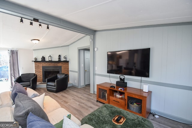 living room featuring a brick fireplace, wood-type flooring, and lofted ceiling with beams