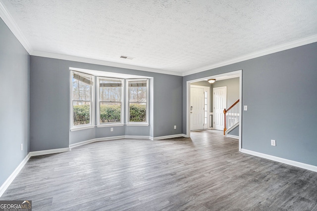 unfurnished room with crown molding, hardwood / wood-style floors, and a textured ceiling