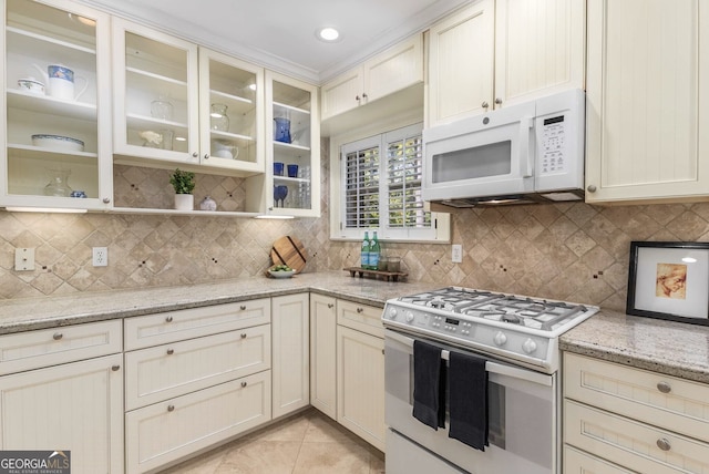 kitchen featuring white appliances, light stone counters, tasteful backsplash, and light tile patterned flooring