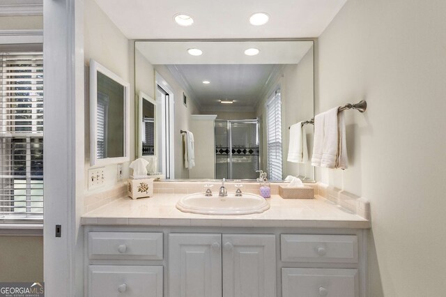 bathroom featuring vanity, crown molding, and a shower with door