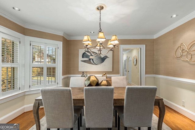 dining area featuring light hardwood / wood-style floors, ornamental molding, and a chandelier