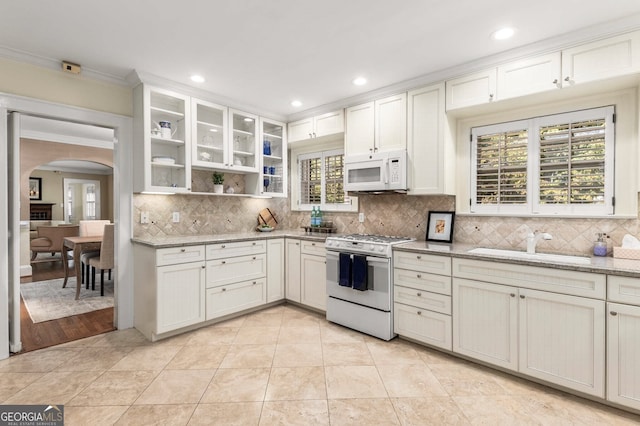 kitchen with light stone countertops, white appliances, tasteful backsplash, sink, and ornamental molding